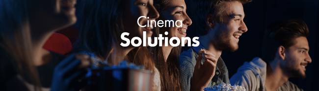 人们一边吃爆米花,一边观看演出。文字为:'Cinema Solutions'